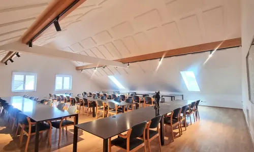 Gro&szlig;er Seminarraum mit Tischen, St&uuml;hlen und Dachschr&auml;gen