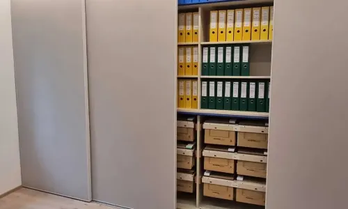 Schiebet&uuml;rschrank ge&ouml;ffnet mit Ordnern und strukturierter Innenaufteilung