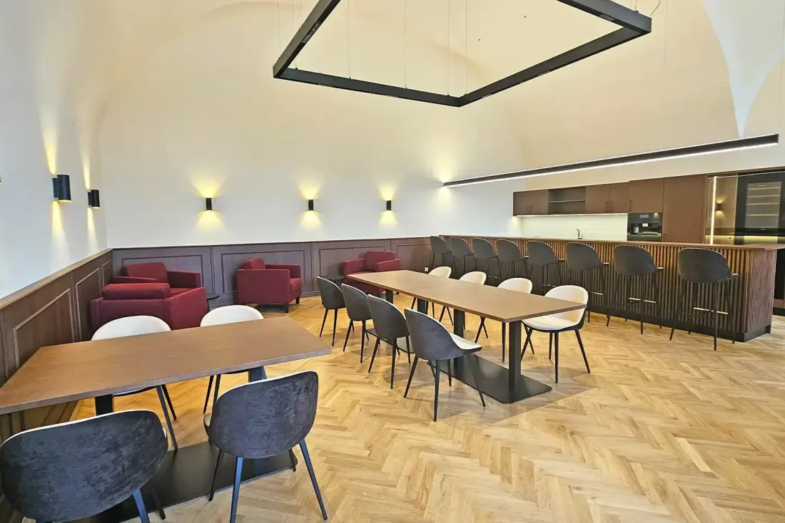 Moderner Aufenthaltsraum mit Tischen, Barbereich und Holzparkett