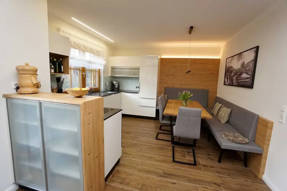 Moderne weiße Küche mit Insel, dunkler Arbeitsplatte und offenen Regalen