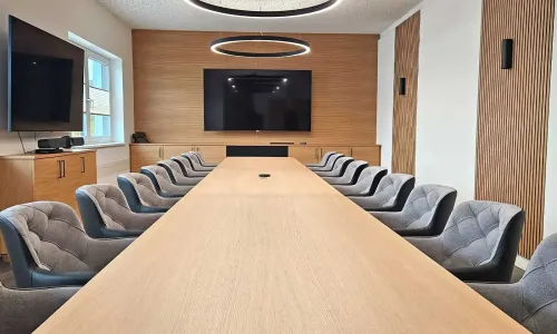Konferenzraum mit langem Tisch, Polsterst&uuml;hlen und moderner Beleuchtung