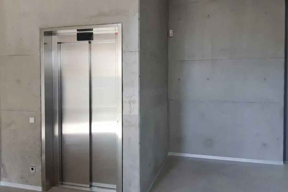 Aufzug in Sichtbetonraum mit minimalistischem Ausbau