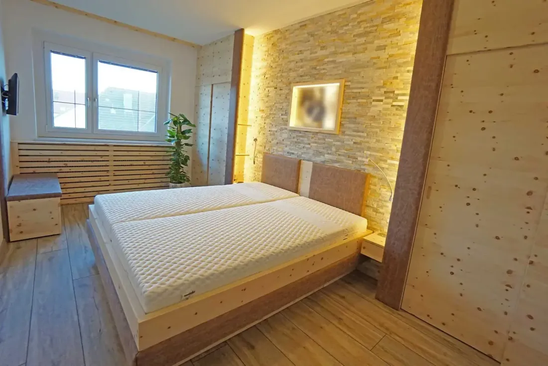  Schlafzimmer mit Holzbett, Steinwand und indirekter Beleuchtung