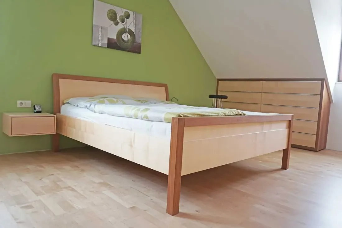 Schlafzimmer mit Holzbett, grüner Wand und schwebendem Nachttisch