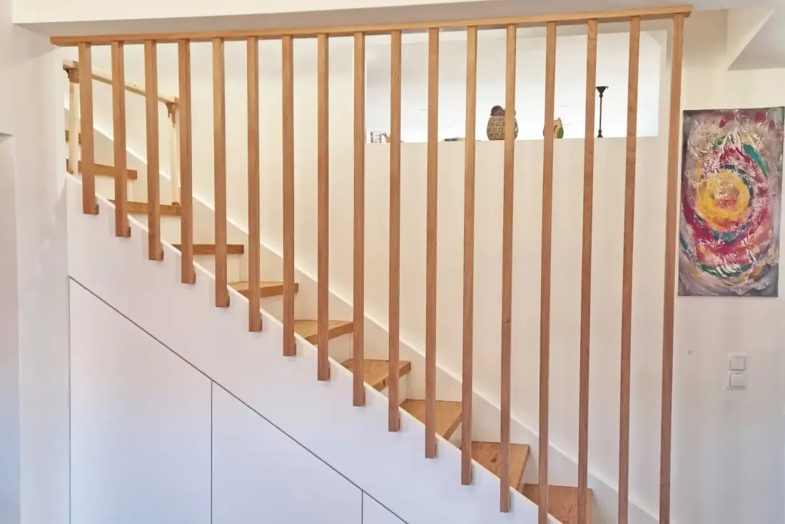 Treppe mit Holzstufen und vertikalem Stabgeländer, modern umgesetzt